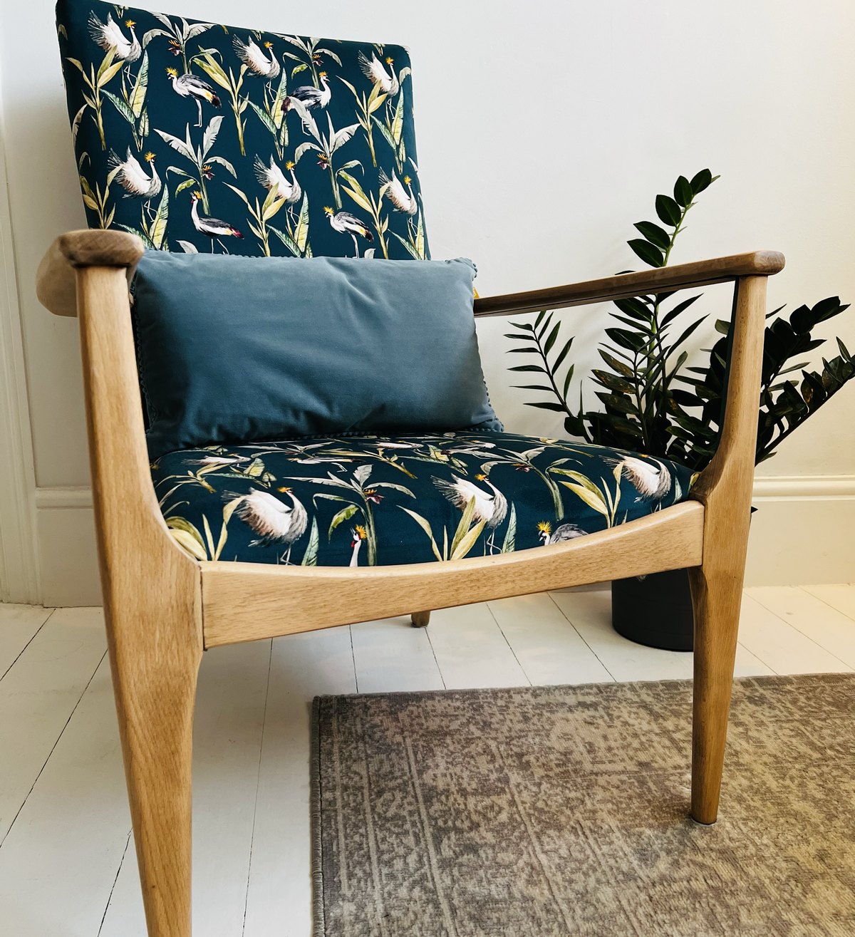 A reupholstered mid-century armchair in teal botanical fabric